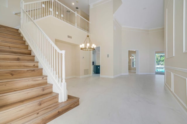 staircase with crown molding, a chandelier, and a high ceiling