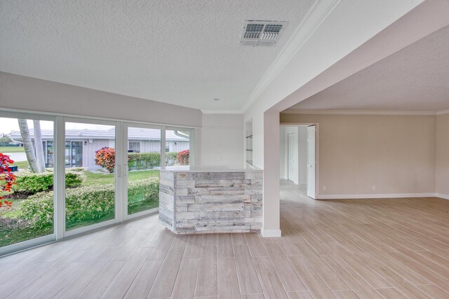 unfurnished room featuring ornamental molding, light hardwood / wood-style floors, and a textured ceiling