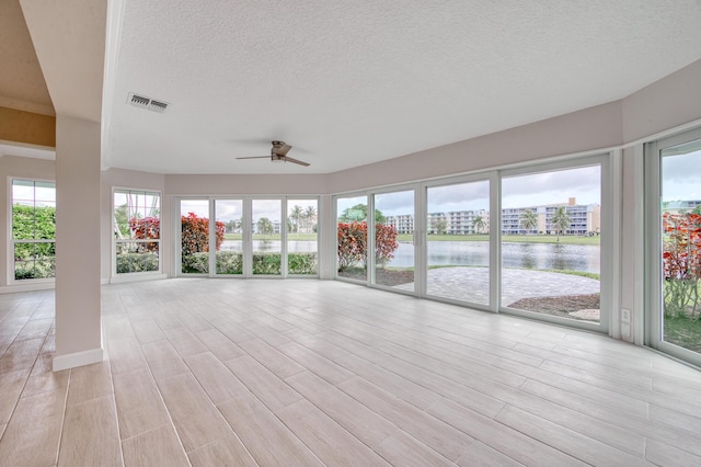 unfurnished sunroom with a water view and ceiling fan