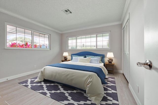 bedroom featuring crown molding, light hardwood / wood-style flooring, and a closet