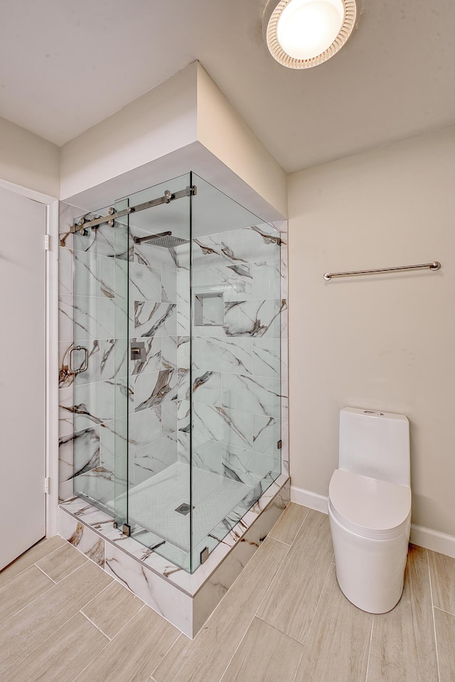 bathroom featuring a shower with shower door and toilet