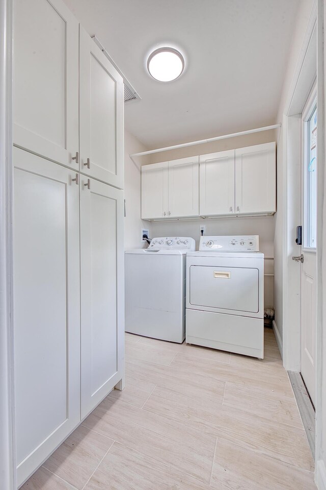 laundry room featuring cabinets, washing machine and dryer, and light wood-type flooring