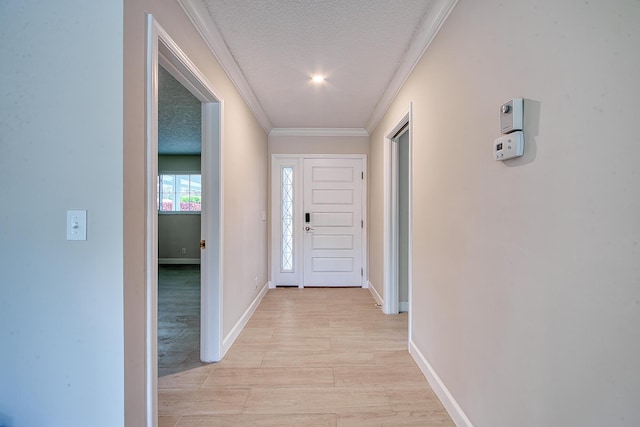 hallway featuring ornamental molding, light hardwood / wood-style floors, and a textured ceiling