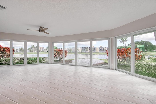 unfurnished sunroom featuring a water view and ceiling fan