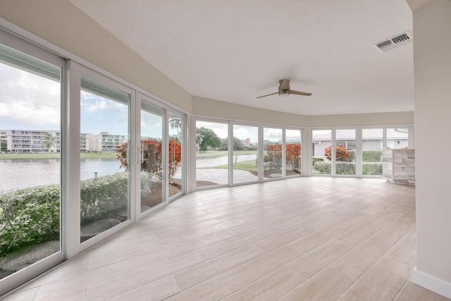 unfurnished sunroom with a water view, ceiling fan, and a healthy amount of sunlight