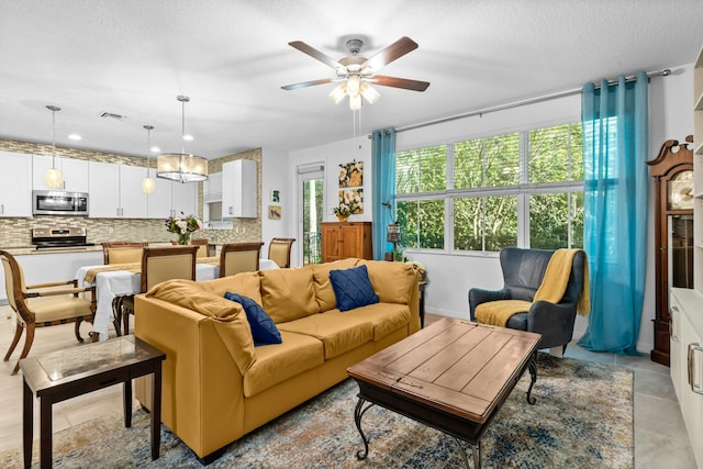 living room featuring light tile patterned flooring, ceiling fan, and a textured ceiling