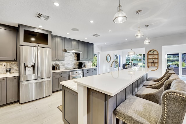 kitchen featuring stainless steel appliances, a kitchen island, a breakfast bar, and decorative light fixtures