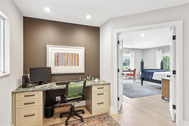 office with built in desk and light wood-type flooring