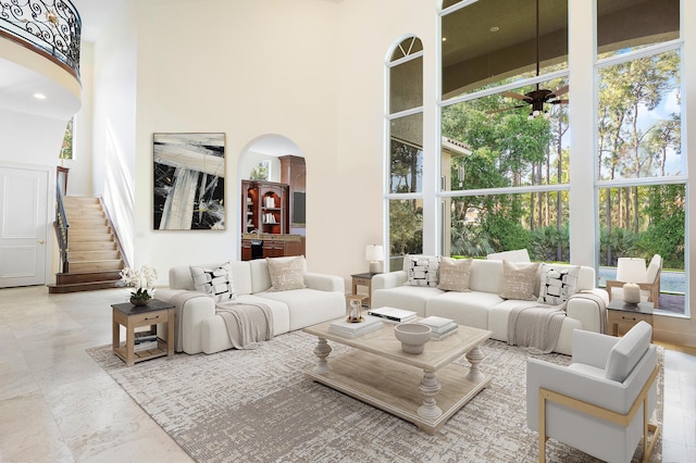 6702 Royal Orchid Cir, Delray Beach, FL 33446 - living room featuring arched walkways, a towering ceiling, plenty of natural light, and stairway