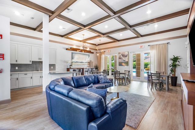 living room with coffered ceiling, sink, beam ceiling, and french doors