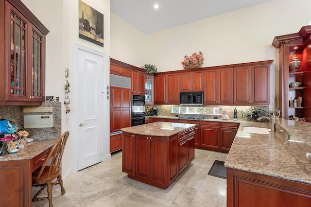 kitchen featuring light stone counters, kitchen peninsula, sink, and black appliances