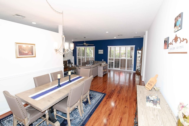 dining room with dark hardwood / wood-style flooring and ceiling fan with notable chandelier