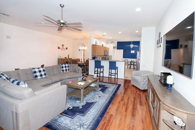 living room featuring hardwood / wood-style flooring and ceiling fan with notable chandelier