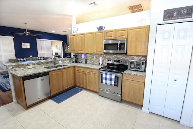 kitchen featuring sink, light stone countertops, kitchen peninsula, and appliances with stainless steel finishes