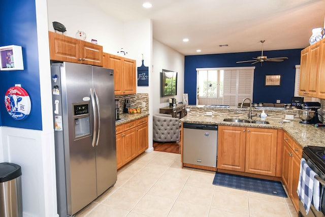 kitchen with sink, light stone counters, light tile patterned floors, appliances with stainless steel finishes, and kitchen peninsula