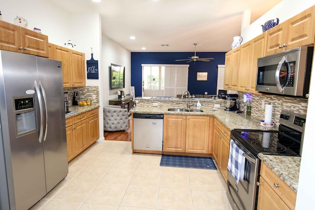 kitchen featuring light stone counters, stainless steel appliances, kitchen peninsula, and sink