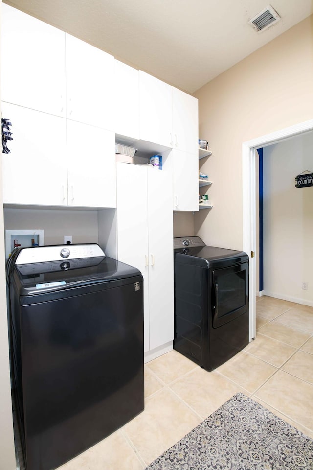 laundry room featuring cabinets, washing machine and dryer, and light tile patterned floors