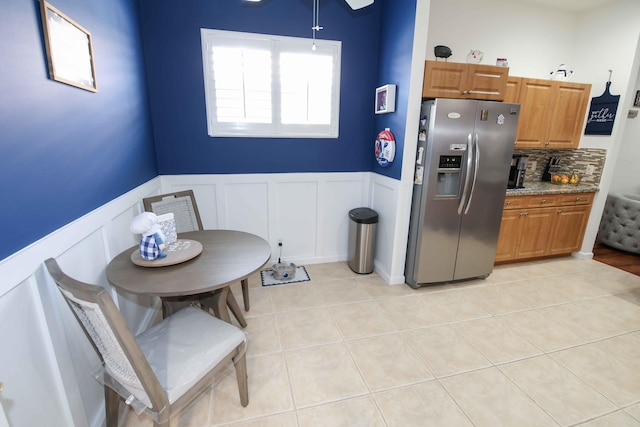 kitchen with tasteful backsplash, light stone countertops, light tile patterned floors, and stainless steel fridge with ice dispenser