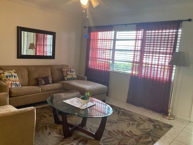 living room featuring light tile patterned floors, crown molding, and ceiling fan