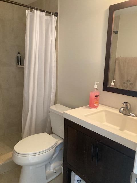 bathroom featuring tile patterned flooring, vanity, toilet, and walk in shower