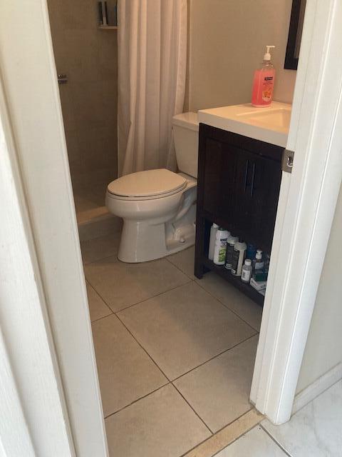 bathroom featuring vanity, tile patterned floors, toilet, and walk in shower