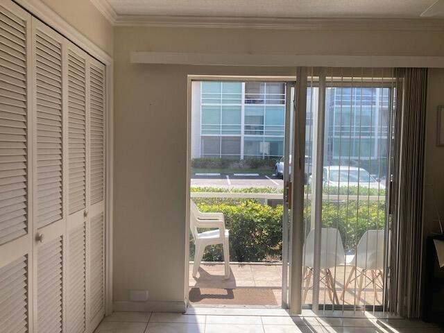 doorway to outside featuring light tile patterned floors, crown molding, and a healthy amount of sunlight