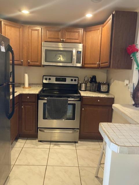 kitchen featuring appliances with stainless steel finishes, kitchen peninsula, and light tile patterned floors