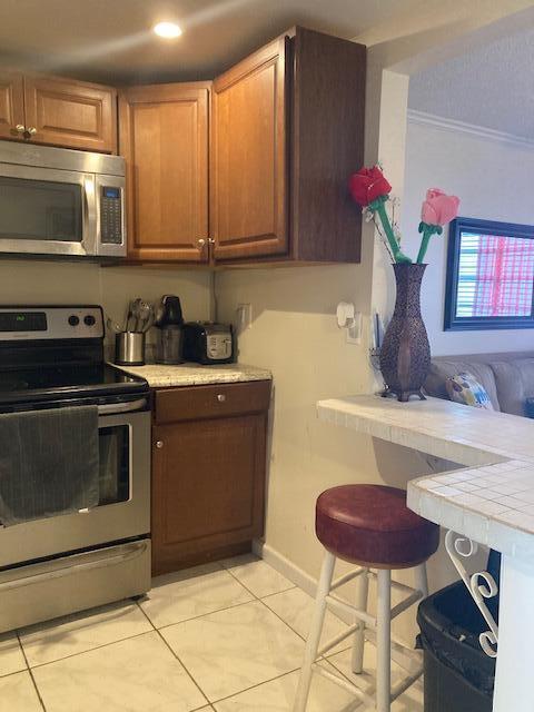 kitchen featuring ornamental molding, appliances with stainless steel finishes, and light tile patterned floors