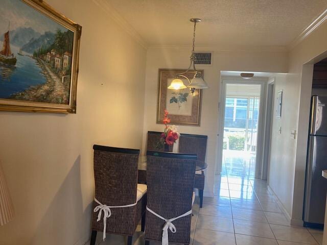 tiled dining area with crown molding and a textured ceiling