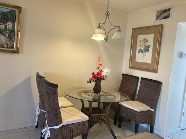 tiled dining room with crown molding and a chandelier