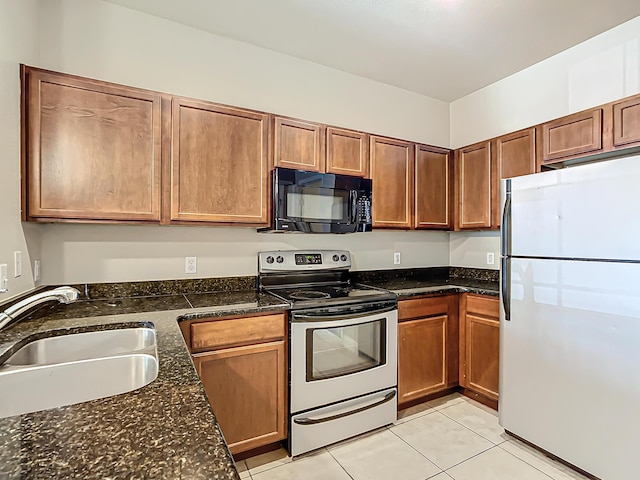 kitchen featuring light tile patterned flooring, sink, stainless steel range with electric cooktop, refrigerator, and dark stone counters