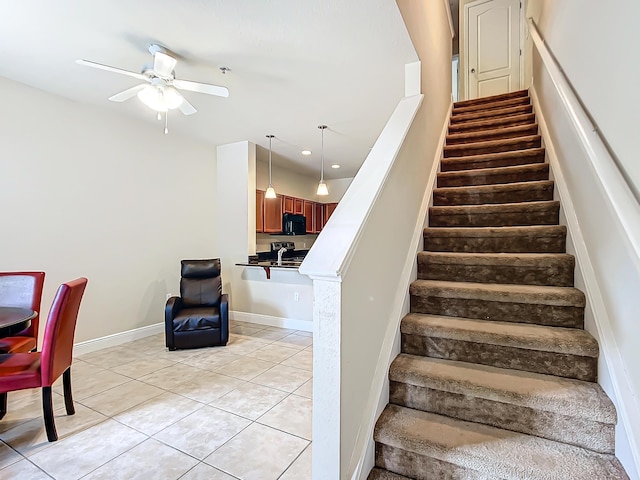 staircase featuring tile patterned flooring and ceiling fan