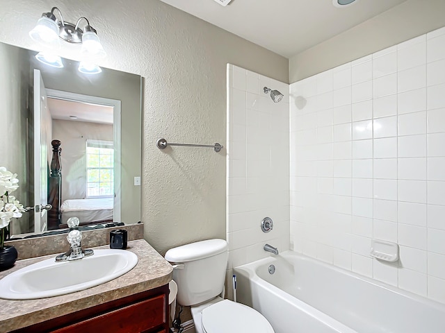 full bathroom featuring tiled shower / bath, vanity, and toilet