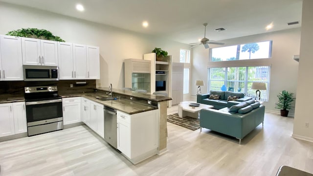 kitchen featuring sink, appliances with stainless steel finishes, white cabinets, kitchen peninsula, and light wood-type flooring