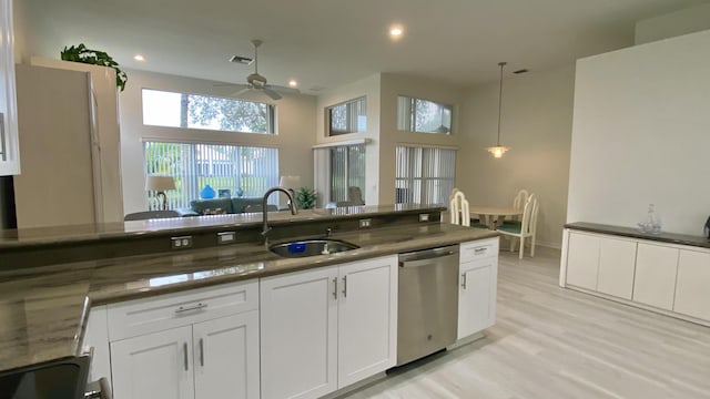 kitchen featuring sink, white cabinetry, hanging light fixtures, light wood-type flooring, and stainless steel dishwasher