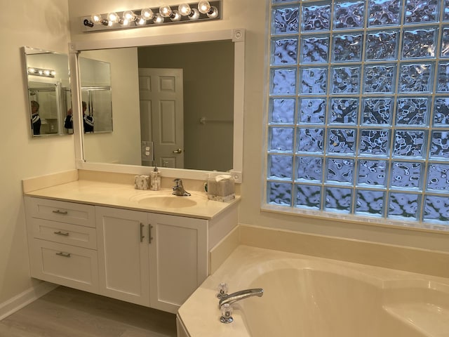 bathroom with vanity, wood-type flooring, and a tub