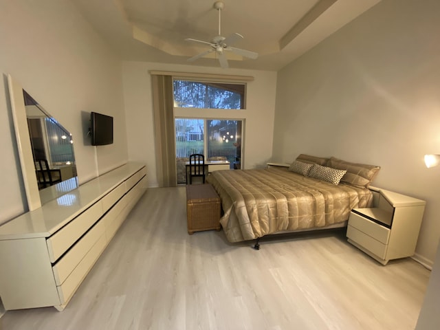 bedroom featuring a raised ceiling and light wood-type flooring