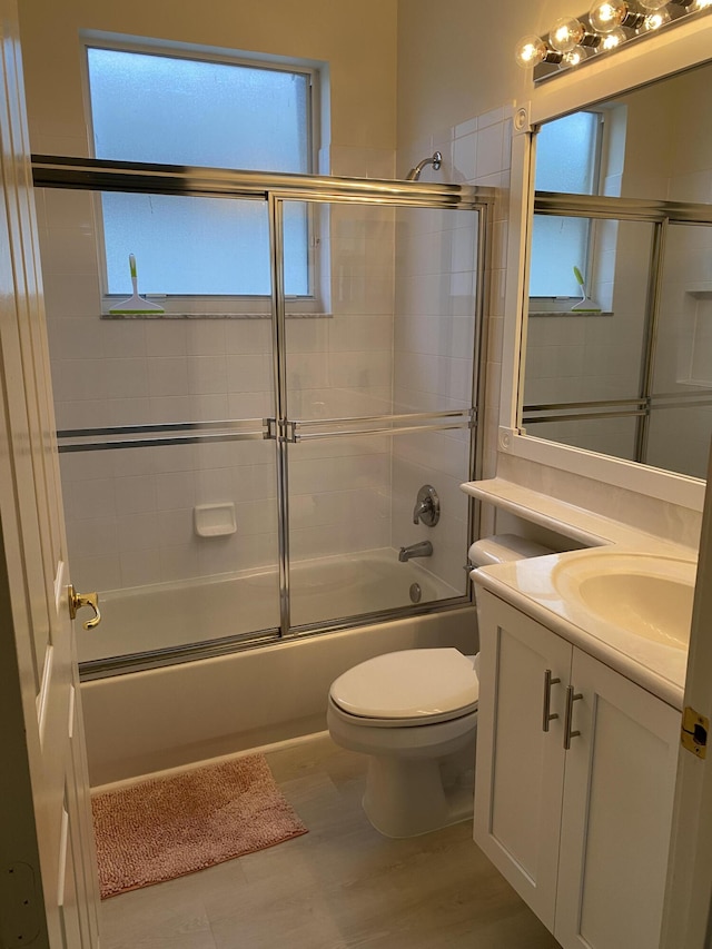 full bathroom with vanity, a wealth of natural light, shower / bath combination with glass door, and toilet