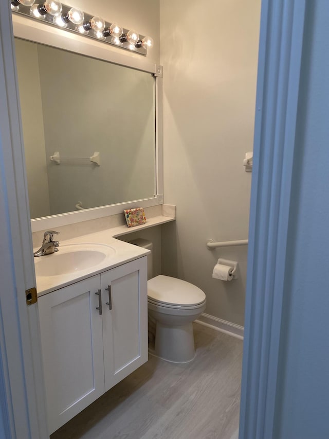 bathroom with hardwood / wood-style flooring, vanity, and toilet