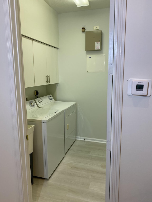 washroom with cabinets, light hardwood / wood-style flooring, and washer and dryer