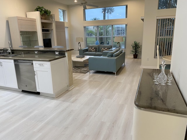 kitchen featuring white cabinetry, sink, a high ceiling, stainless steel dishwasher, and light hardwood / wood-style flooring