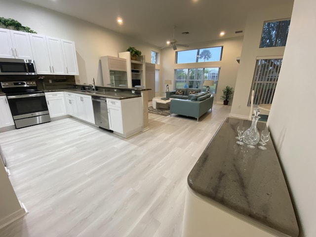 kitchen featuring sink, light wood-type flooring, kitchen peninsula, stainless steel appliances, and white cabinets