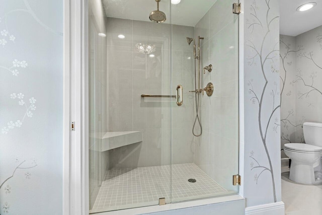 bathroom with toilet, wallpapered walls, and a shower stall