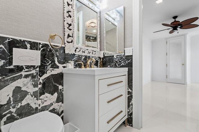 half bathroom with ceiling fan, vanity, and toilet