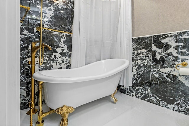 bathroom with a freestanding tub and tile walls