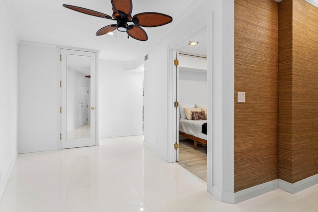 corridor featuring light tile patterned floors, baseboards, and crown molding