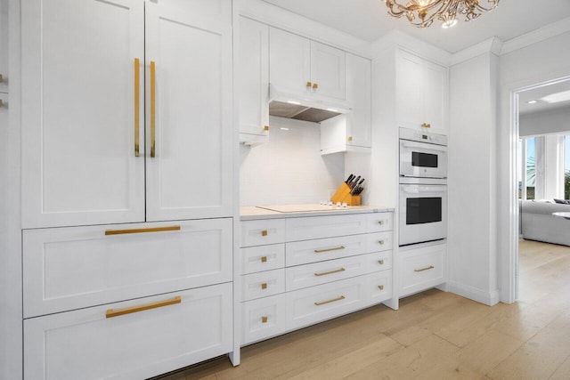 kitchen featuring white double oven, light countertops, electric cooktop, white cabinets, and under cabinet range hood