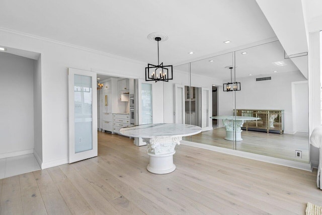 unfurnished dining area with visible vents, an inviting chandelier, light wood-style floors, ornamental molding, and baseboards