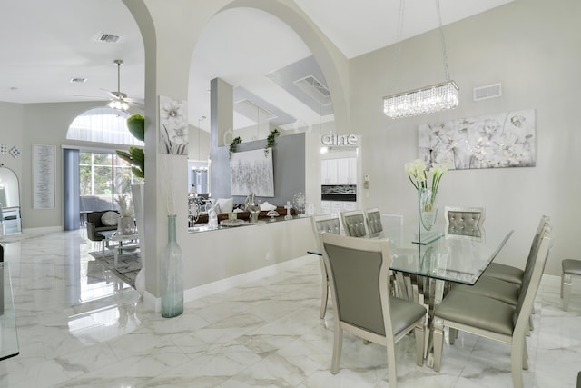 dining space with ceiling fan and a towering ceiling