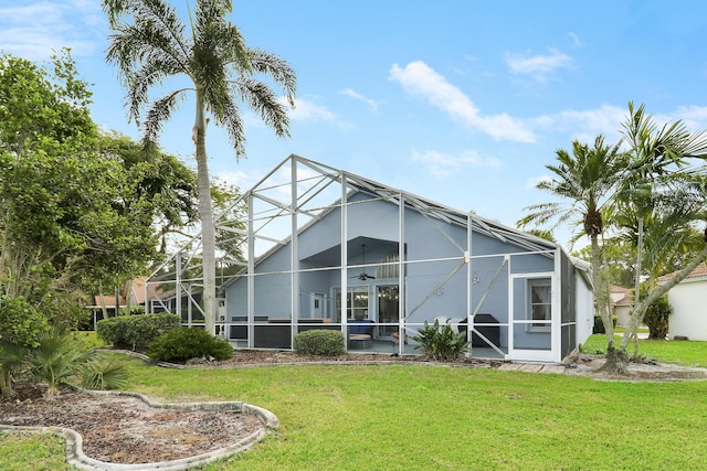 rear view of property with a yard, a lanai, and ceiling fan